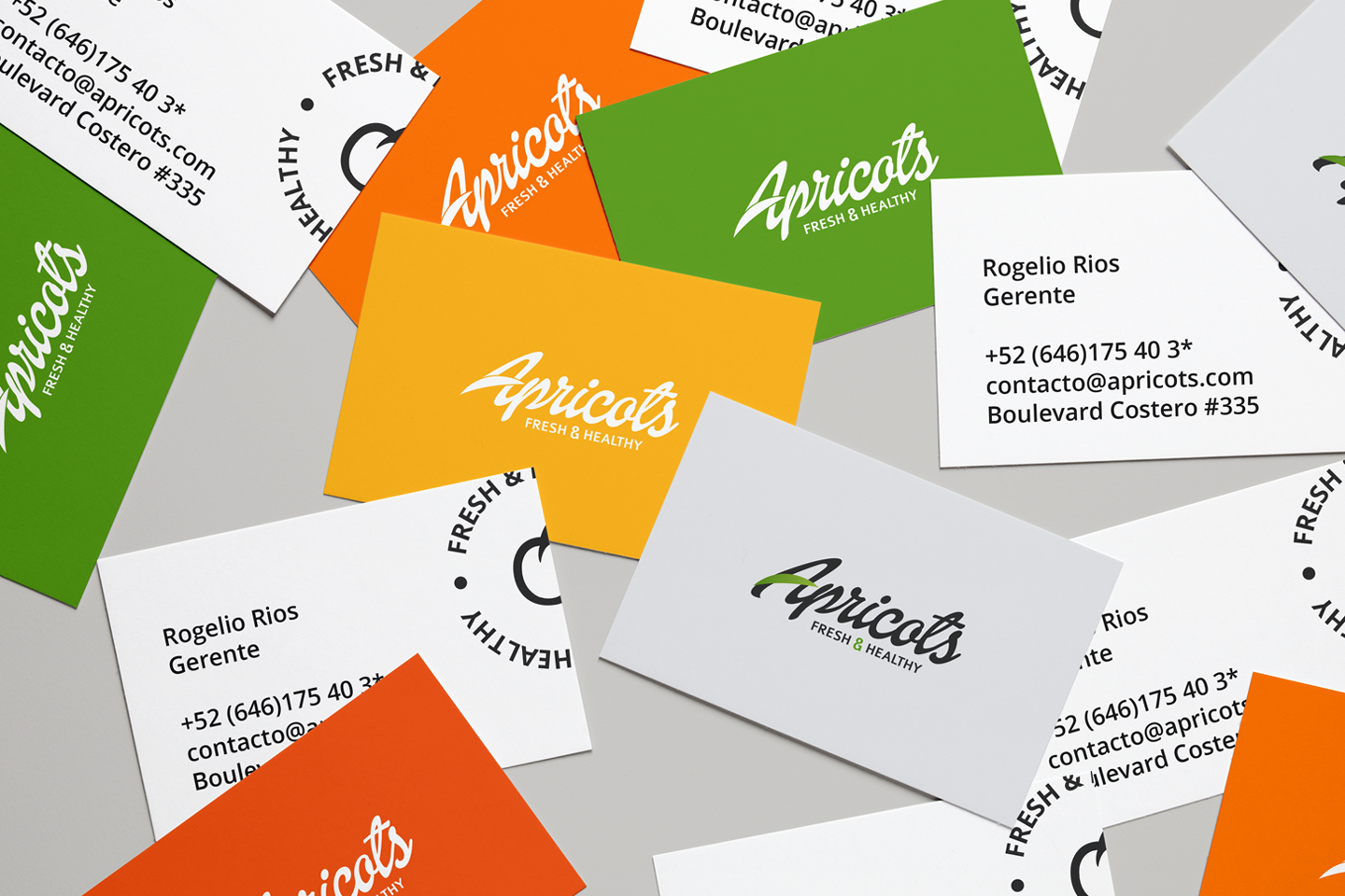Tarjetas de presentación de Apricots en verde, naranja, amarillo y blanco esparcidas sobre una superficie.